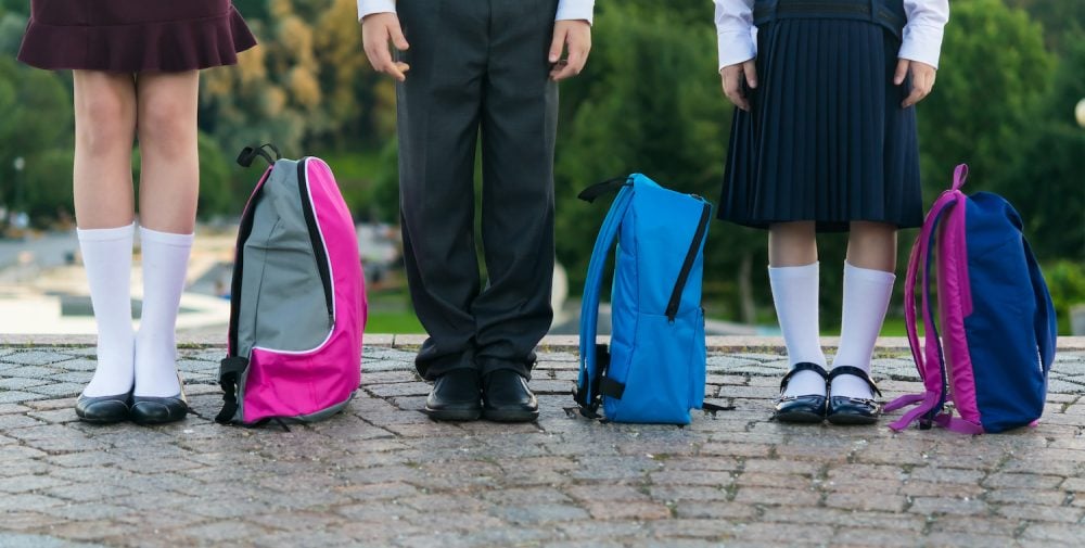 School children with backpacks stand in the park ready to go to 